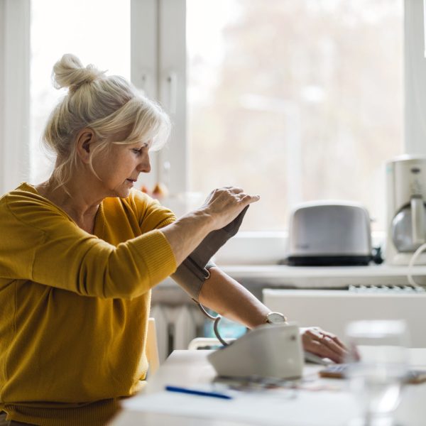Senior woman measuring blood pressure at home